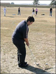 Junior Cody Flanders chips a shot during golf practice.