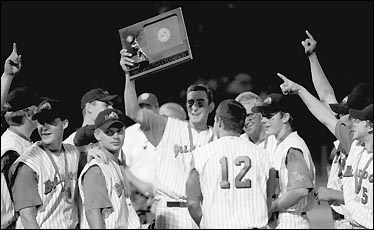 The baseball players gather around their trophy